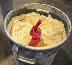 A bucket of feed with a red scoop.