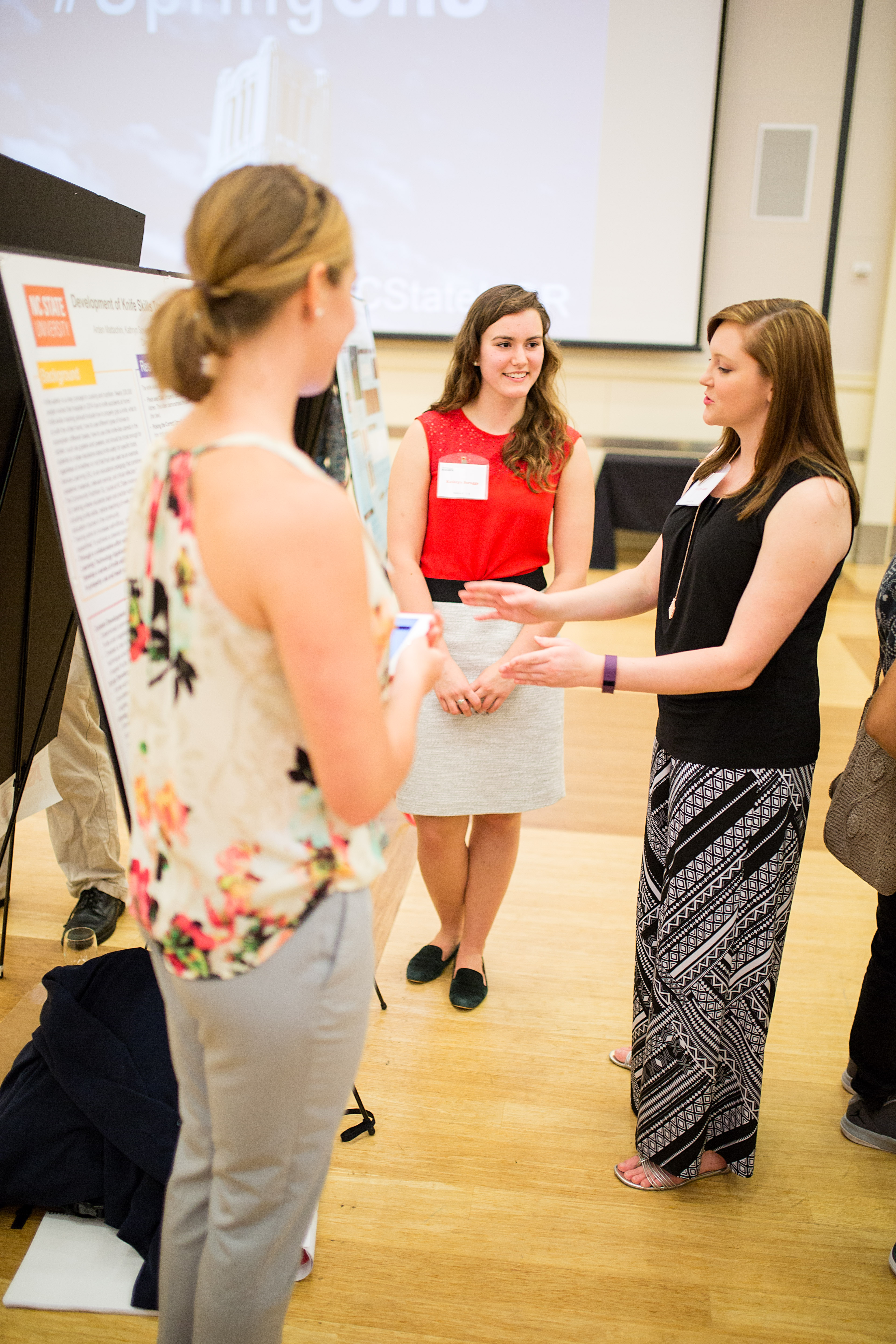 From left to right: Arden Mattachini and Kati Scruggs discuss the importance of knife safety with poster visitor.