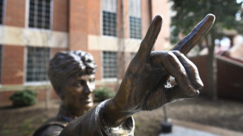 up close photo of statue of former NC State Wolfpack women's coach Kay Yow with hand in classic 