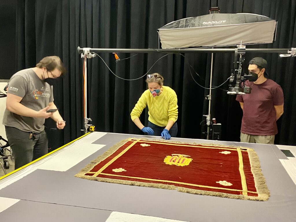 Photo of team preparing a 17th century red silk and velvet cardinal's banner from Spain for scanning