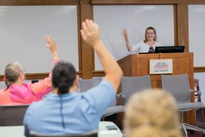 Associate Vice Provost for Academic Technology Innovation Donna Petherbridge welcomes faculty at the 2018 Summer Shorts in Instructional Technologies program. Petherbridge stands at front of room interacting with faculty. Faculty have hands raised. 