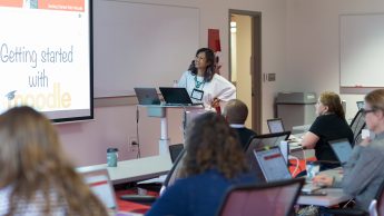Instructional Technologist Arlene Mendoza-Moran leads a session about Moodle at the 2018 Summer Shorts in Instructional Technologies program. Arlene is at the front of a classroom looking at a screen that says 