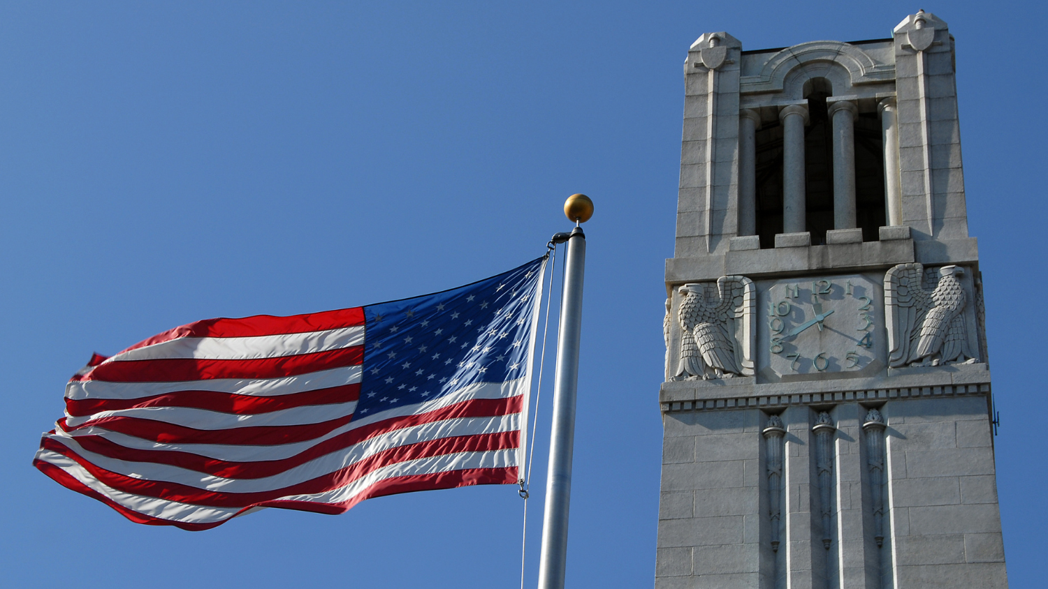 NC State belltower and the American Flag.