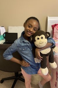 Hailee, Lockett's daughter, poses as she holds a stuffed monkey.