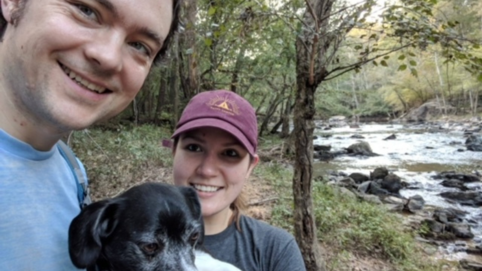 Vienrich poses with her fiancé and dog at the Eno River in Durham, North Carolina.