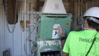 Associate Professor Adam Fahrenholz demonstrating the magnetic filter of the hammer mill. This filter picks out debris from the raw materials to be ground by the hammers in the chamber below.