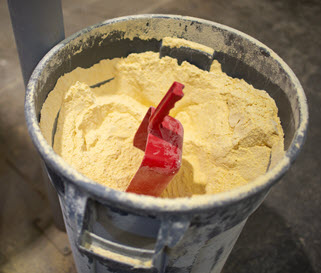 A bucket of feed with a red scoop.